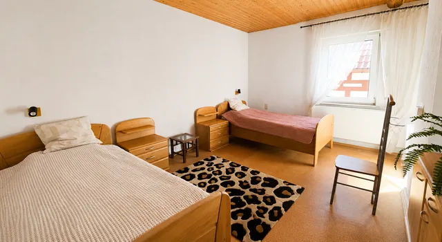 Helles Schlafzimmer mit zwei Einzelbetten und Holzdecke