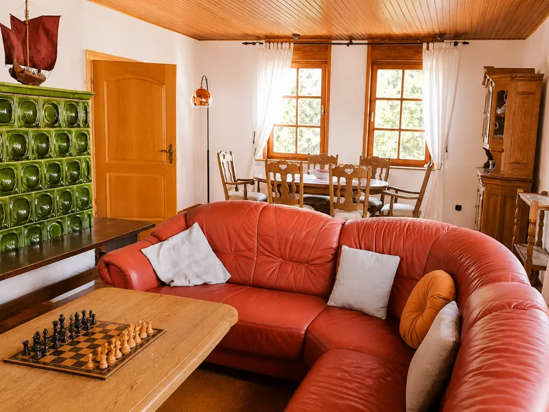 Gemütliches Wohnzimmer mit Kachelofen, Ledersofa und Fernseher